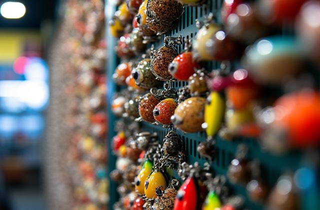 Close-up shot of a vibrant wall of fishing lures, sparkling and organized by type and color within Caribou Cast store.